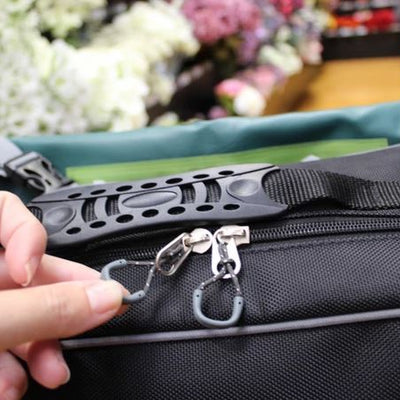 The image shows a close-up of a woman's hand gripping the easy-pull zips on the Hi-Vis Flexi Mobility Bag