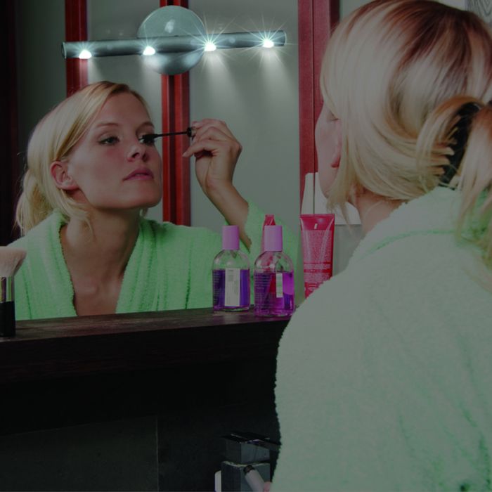 the image shows the life max two way light wand being used to illuminate a dressing table mirror and a young woman applying makeup