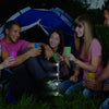 the image shows the lifemax two way light wand in its stand vertically being used to illuminate a camping space and a group of young people drinking from plastic cups