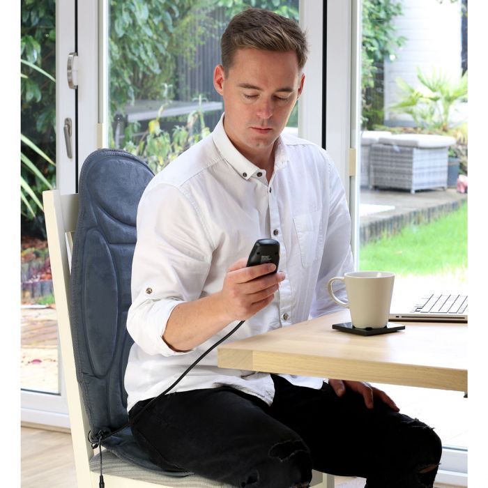 the image shows a young man using the remote on the Lifemax heated back and seat massager