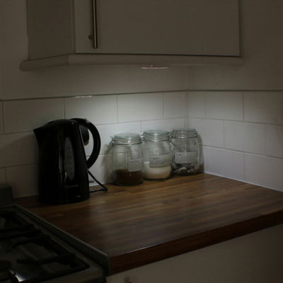 the image shows lifemax remote control wireless LED lights being used as uplighters beneath a kitchen cupboard to light a worktop area with kettle