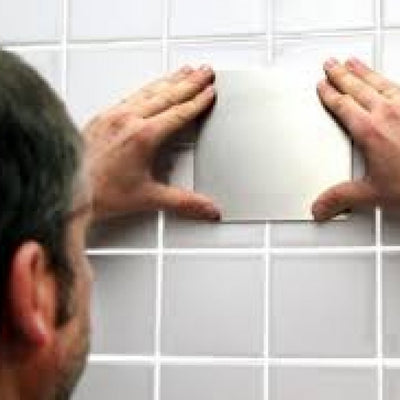 shows a man fixing a Mobeli Cardan Steel Plate to a grey tiled wall