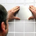 shows a man fixing a Mobeli Cardan Steel Plate to a grey tiled wall