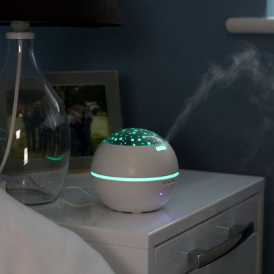 the image shows the Lifemax projection humidifier on a bedside table with both mist and light