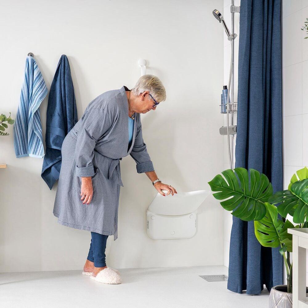 Lady about to sit on Shower seat , she is pulling the seat down