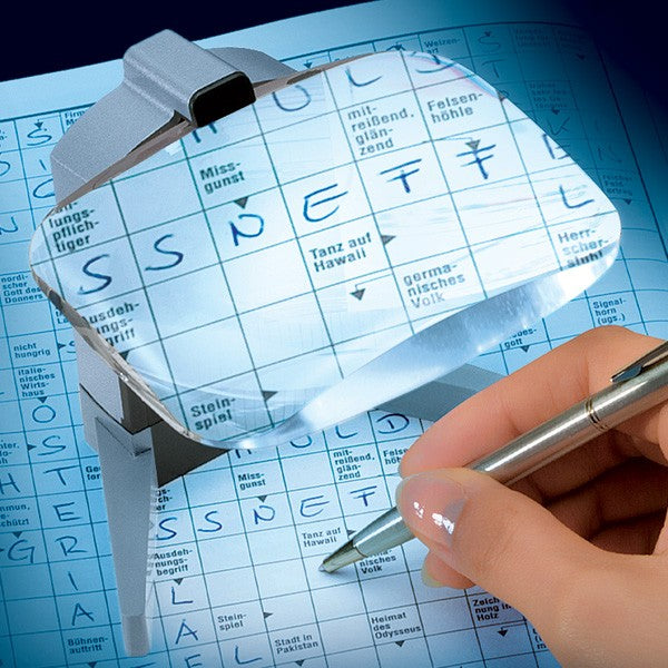 the image shows the eschenbach scribolux illuminated stand magnifier being used to complete a german word puzzle