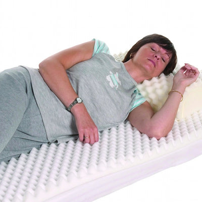 the image shows a woman lying on her side on the Harley Ripple Mattress Topper with Cover