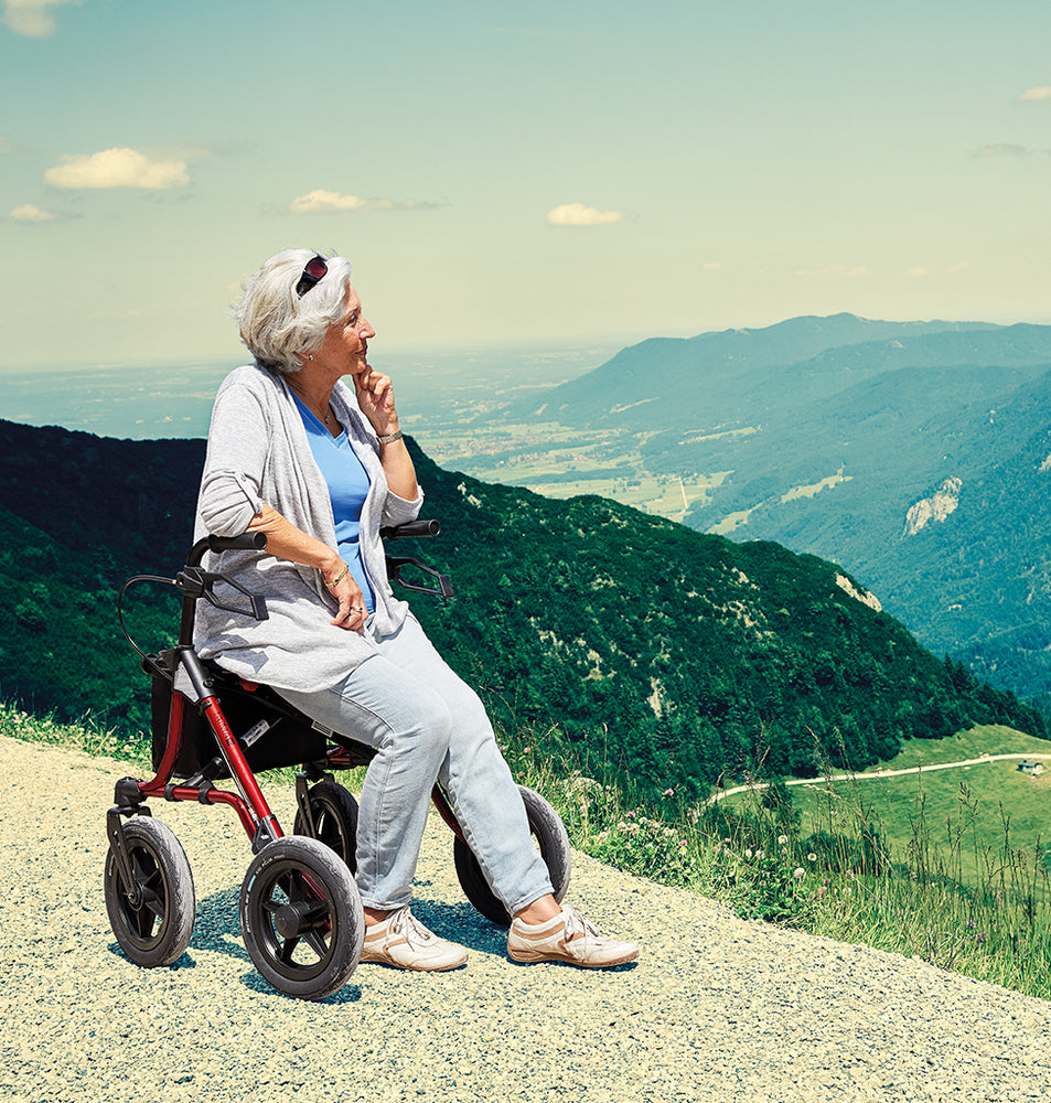 shows a woman resting on a Dietz Taima Rollator in a picturesque setting