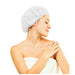 shows a woman wrapped in a white towel wearing a Moistened Shampoo Cap