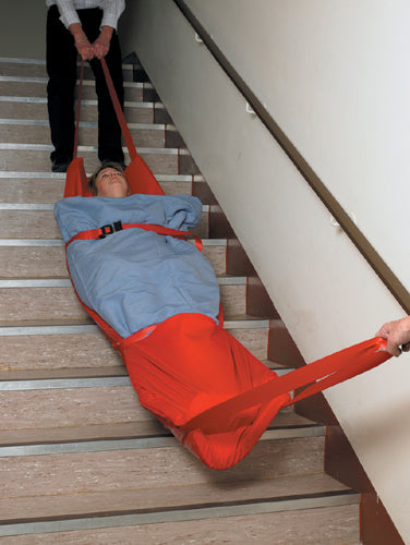 Two medical employees using the Evacuation Sledge to move someone on some stairs